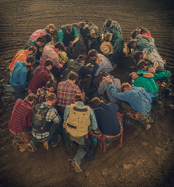 A group of Christian cowboys pray together before a bull riding and rodeo